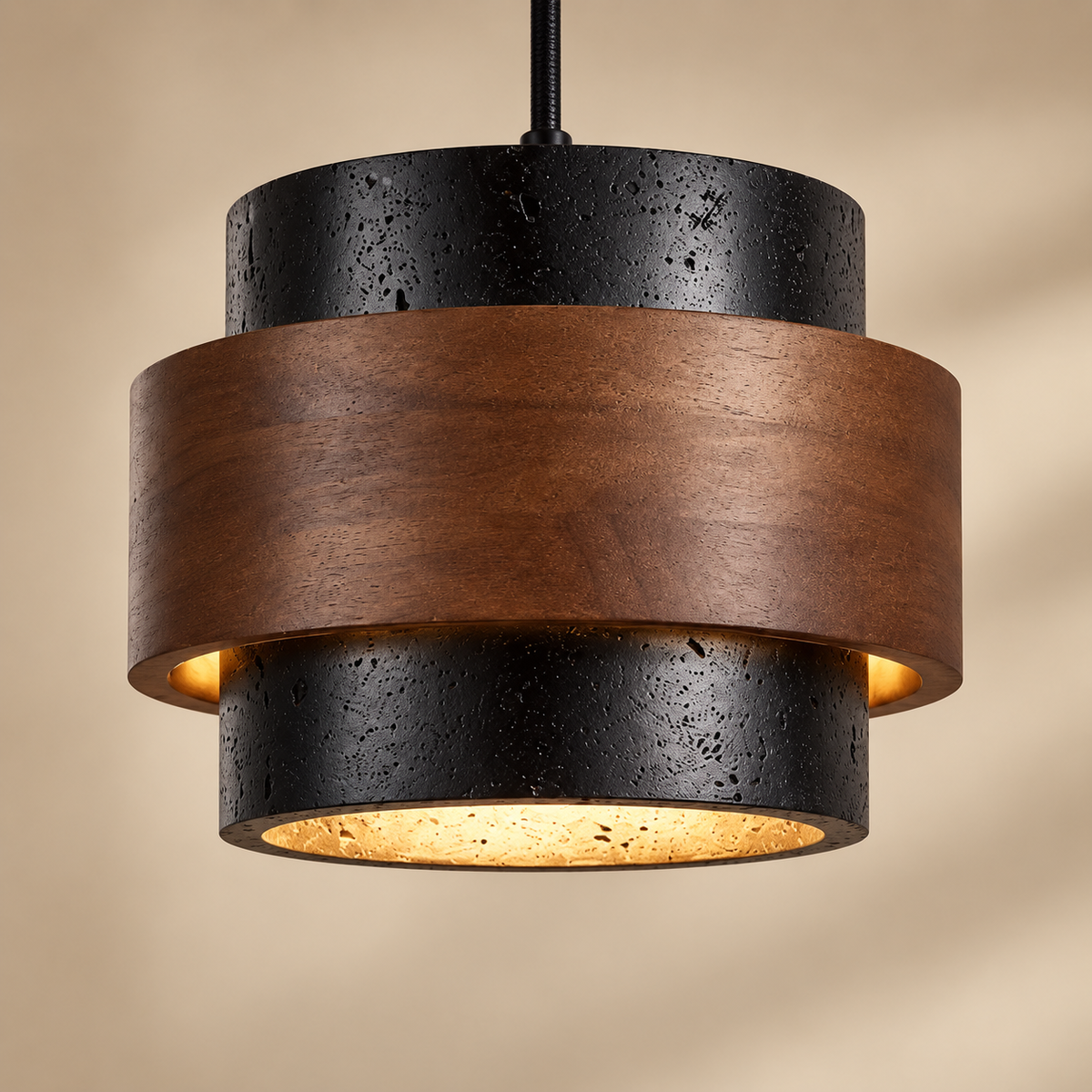 A modern pendant light fixture with two textured black metal cylinders and a wide brown wood band around the middle, shown against a warm beige background.