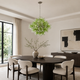Modern dining room with a round table, chairs, and a decorative green chandelier.