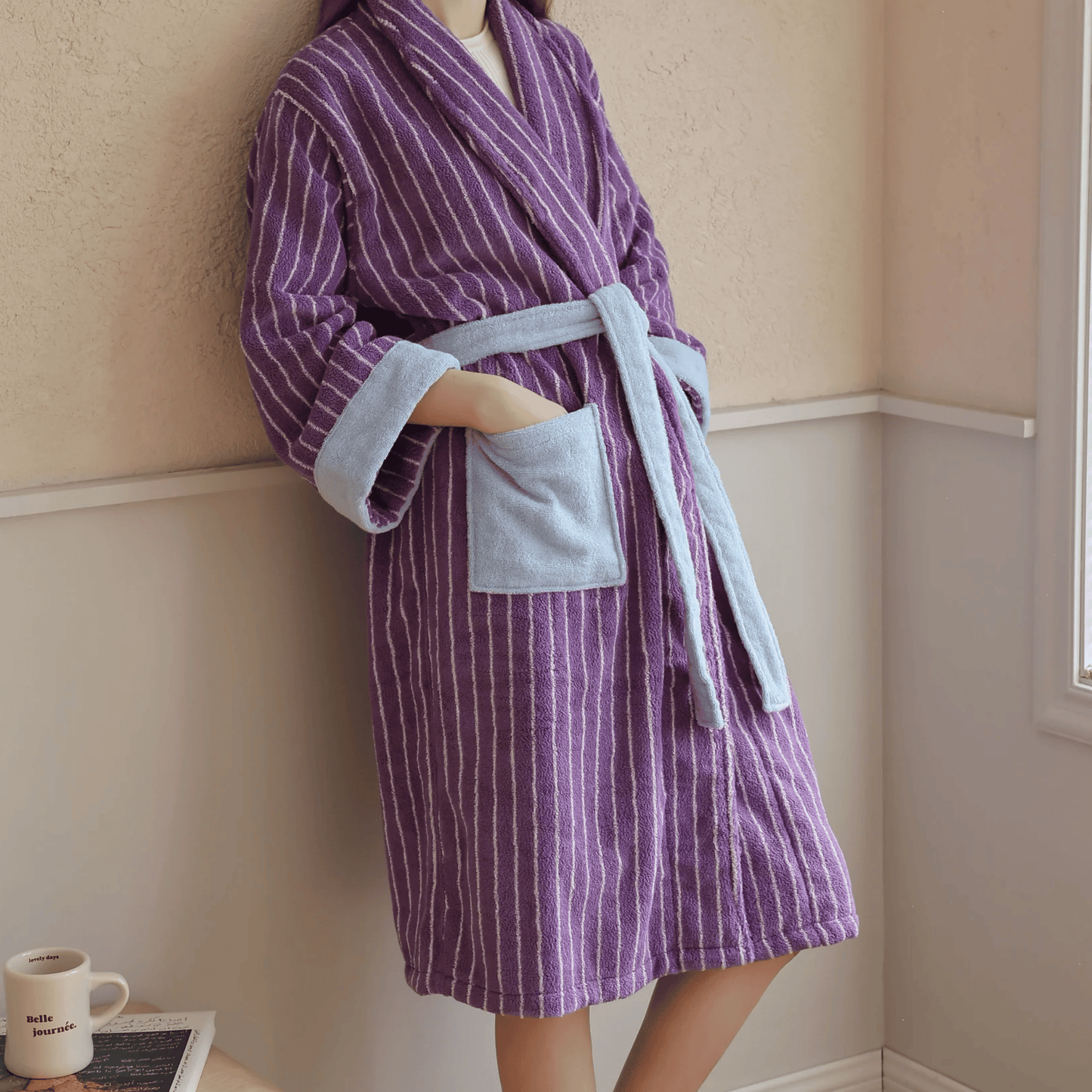 Person wearing a purple and gray striped robe in a room.