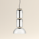 Modern pendant light with three cylindrical glass shades on a beige background