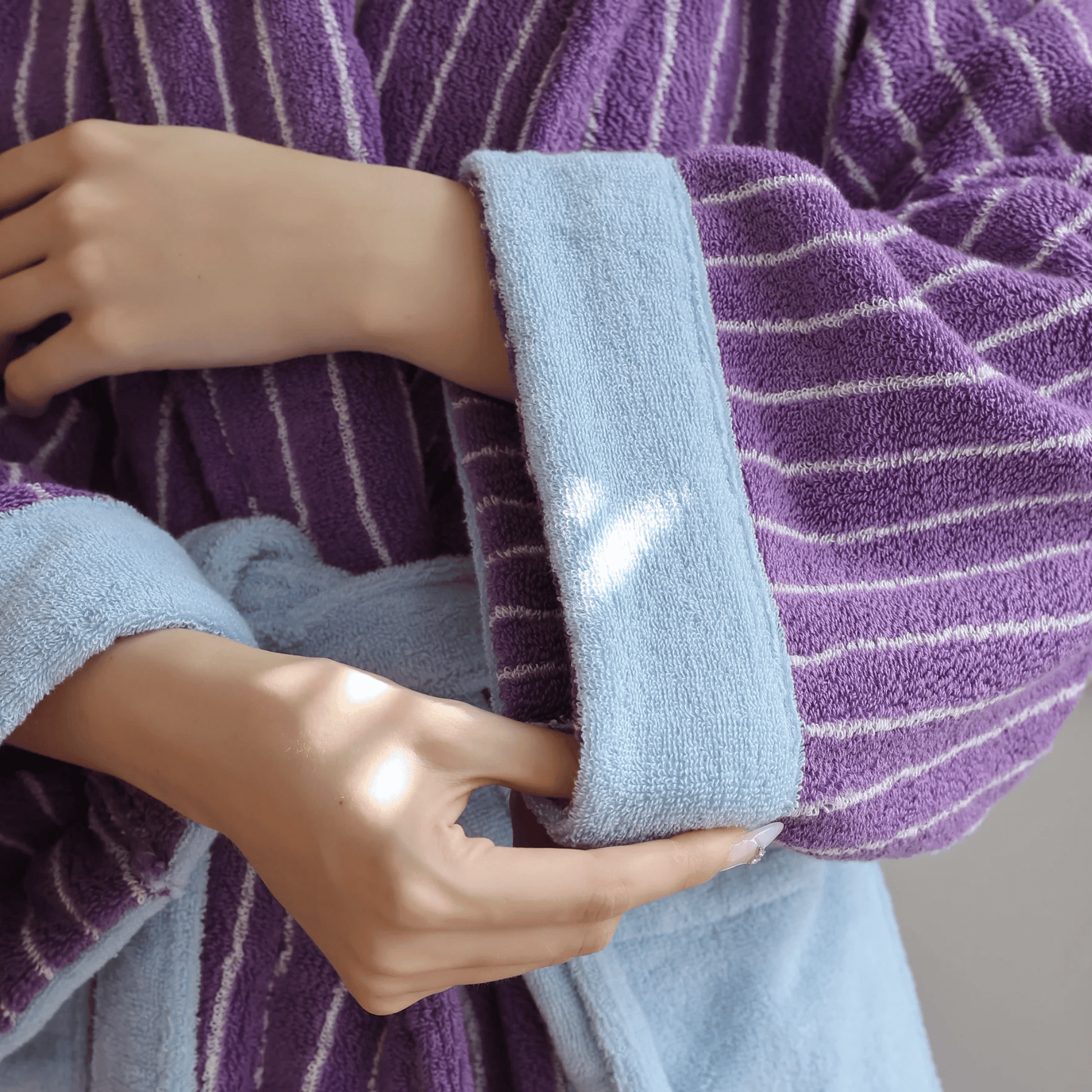 Person holding a light blue towel with a heart design against a purple striped background