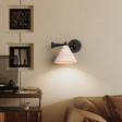 Wall-mounted lamp with a cone-shaped shade in a cozy living room setting.