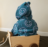 Blue hooded towel with smiley face pattern on a wooden toy cart.