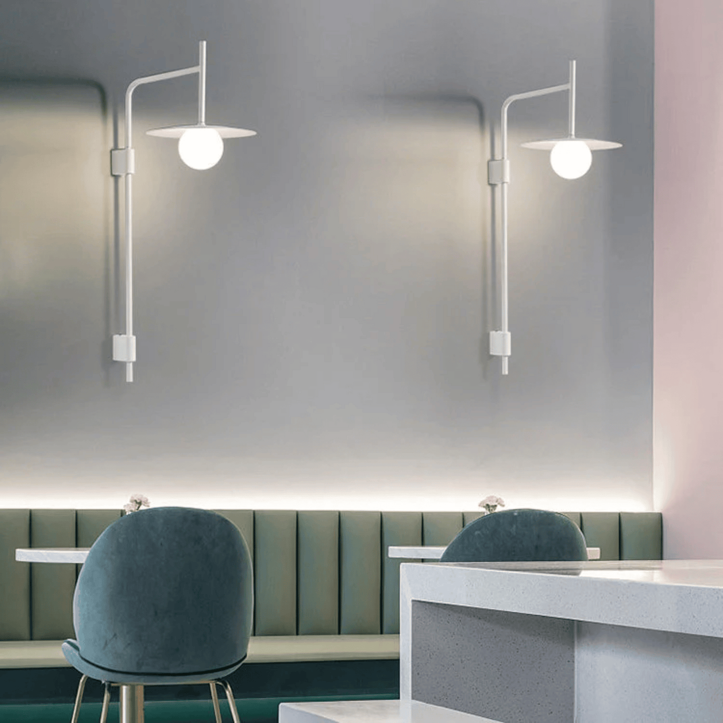 Modern wall lights in a minimalistic interior setting with green chairs and a gray bench.