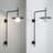 Modern wall-mounted light fixture with a black frame and white bulb on a plain background.