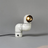 A white elbow-shaped desk lamp illuminating a book with a focused beam of light, placed on a neutral-colored surface.