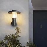 Minimal white facade featuring a stylish black and glass outdoor wall lamp near the doorway