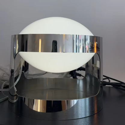 Modern table lamp with chrome base and white globe shade on a dark surface.