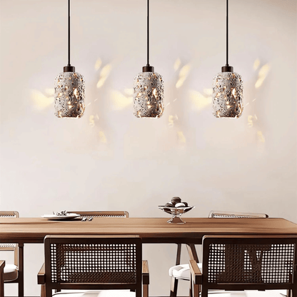 Three pendant lights hanging above a dining table with chairs.