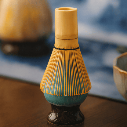 Ceramic whisk holder with yellow top and blue base on a wooden surface