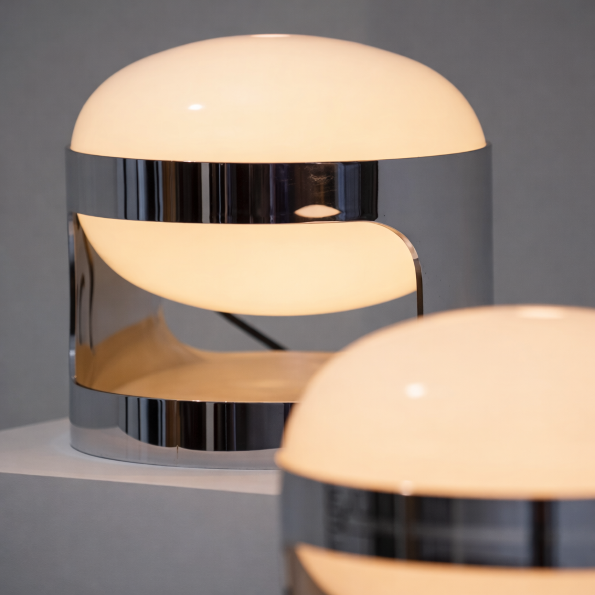 Modern table lamp with a metallic base and white shade on a gray background