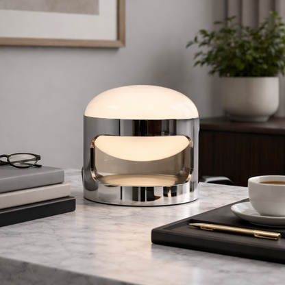 Modern table lamp on a marble surface with books, a cup, and a plant in the background.
