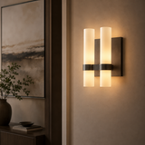 Modern wall sconce with two cylindrical lights on a neutral wall.