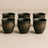 Set of six black ceramic cups on a beige background