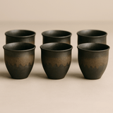 Set of six black ceramic cups on a beige background
