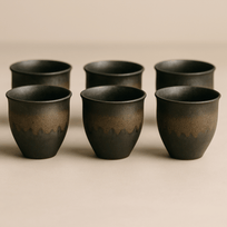 Set of six black ceramic cups on a beige background
