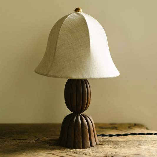 Small table lamp with a white shade and brown base on a wooden surface.