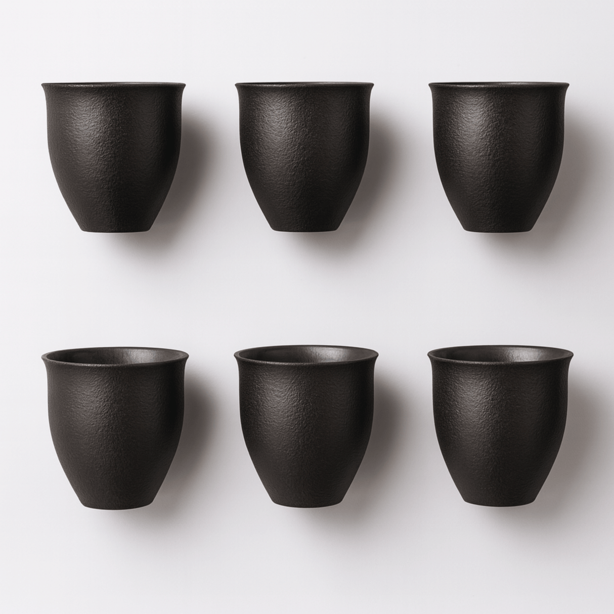 Six black ceramic cups arranged in two rows on a white background