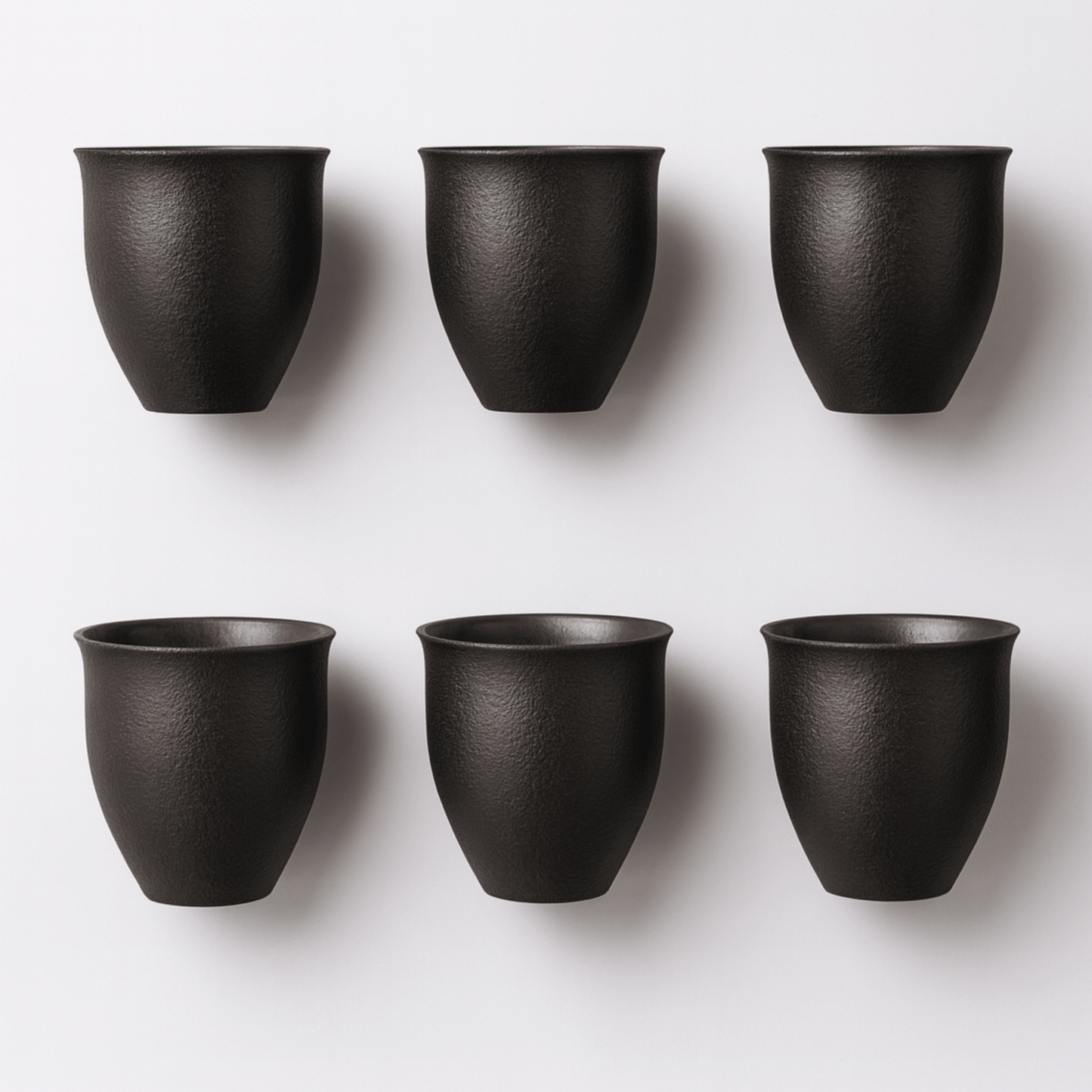 Six black ceramic cups arranged in two rows on a white background