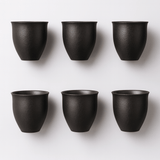 Six black ceramic cups arranged in two rows on a white background