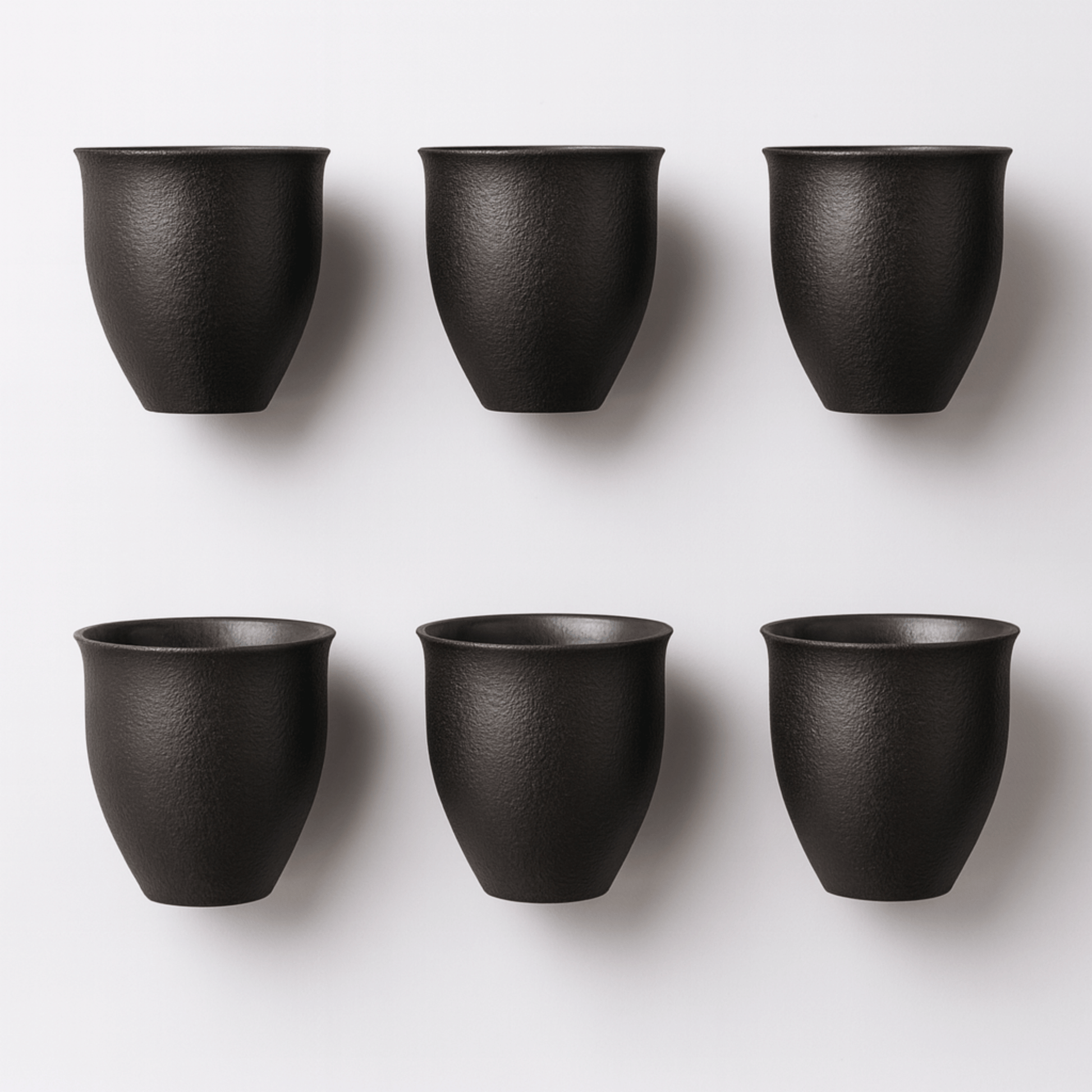 Six black ceramic cups arranged in two rows on a white background