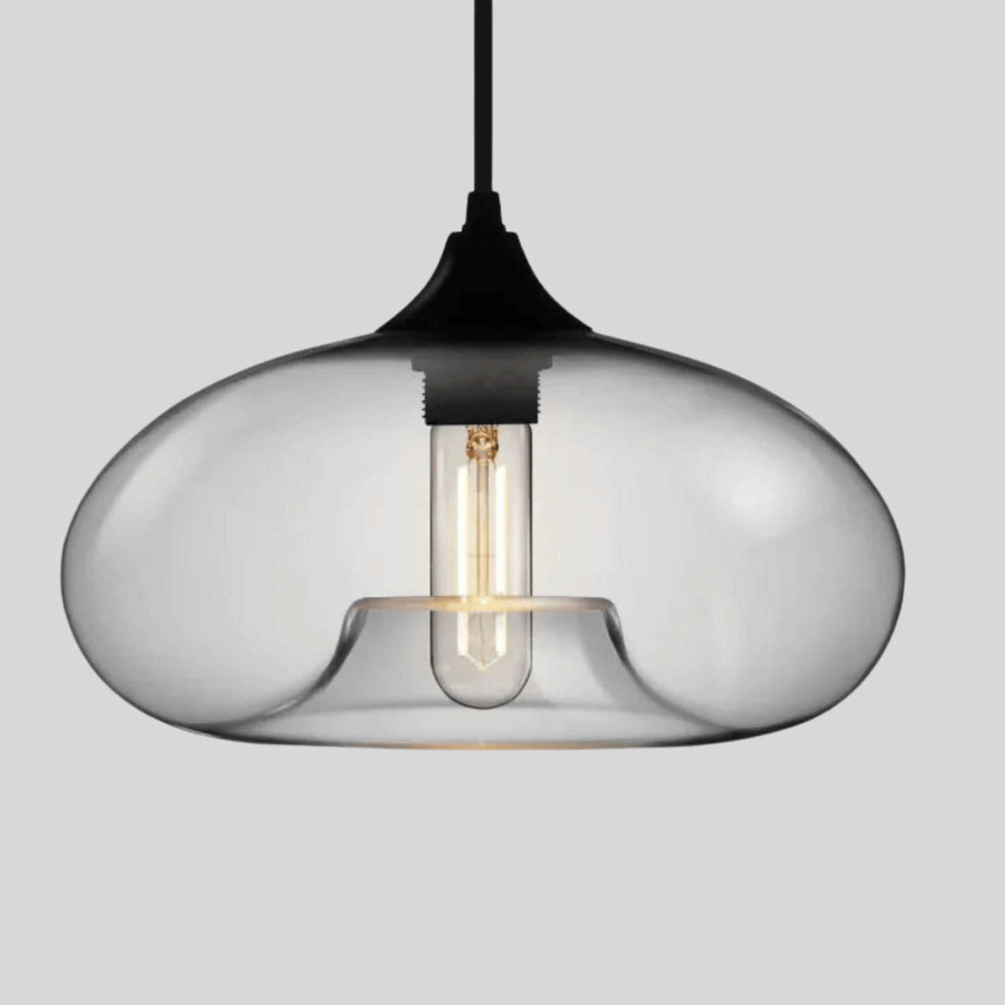 Clear glass pendant light with black fixture on a gray background