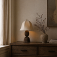 Napoleon Chocolat table lamp on a wooden side table with a vase of dried flowers and books.