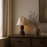 Napoleon Chocolat table lamp on a wooden side table with a vase of dried flowers and books.