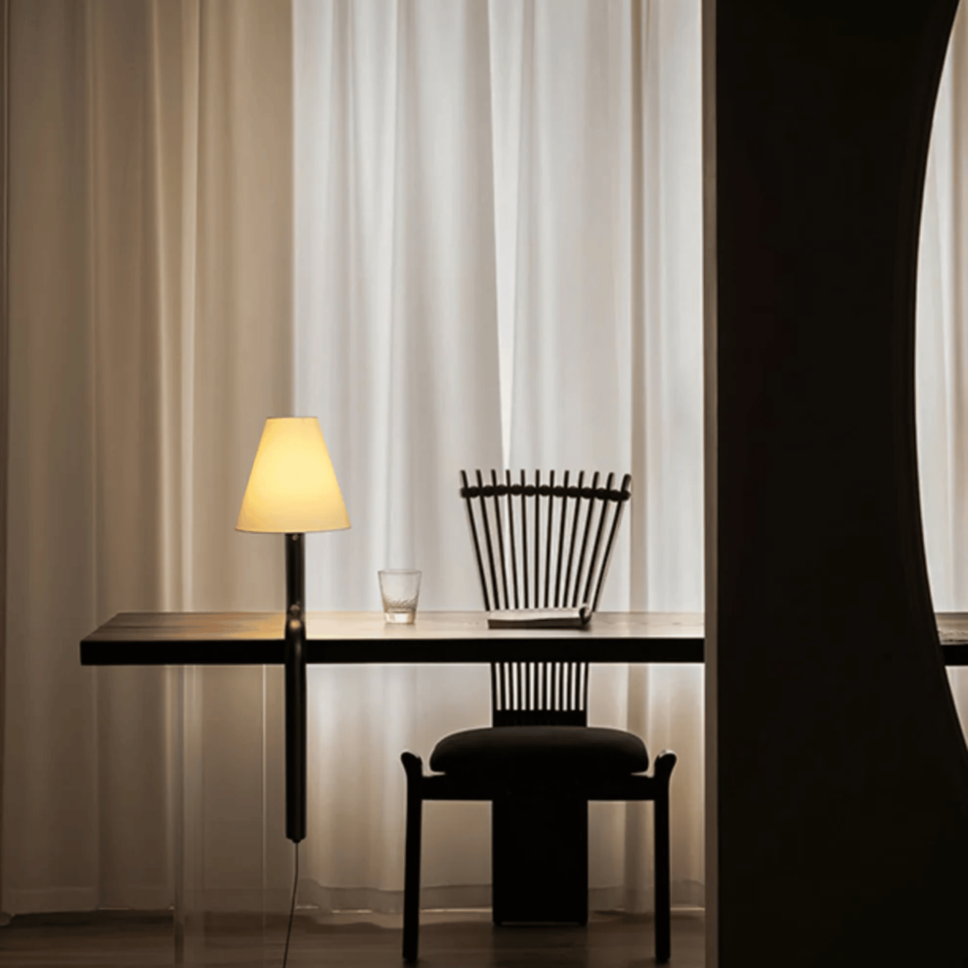 Modern black desk with chair and lamp against a curtain backdrop