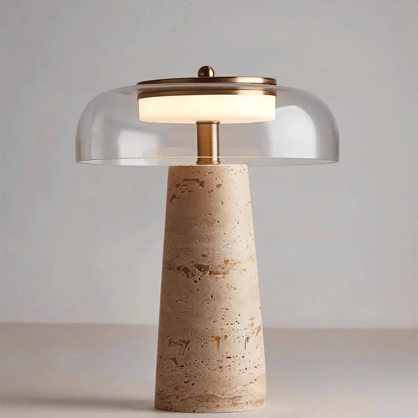 Table lamp with a beige stone base and glass shade on a neutral background