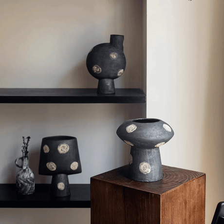 Black ceramic vases with gold accents on a wooden pedestal and shelves.
