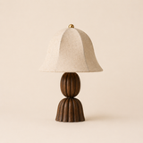 Table lamp with wooden base and beige fabric shade on a beige background