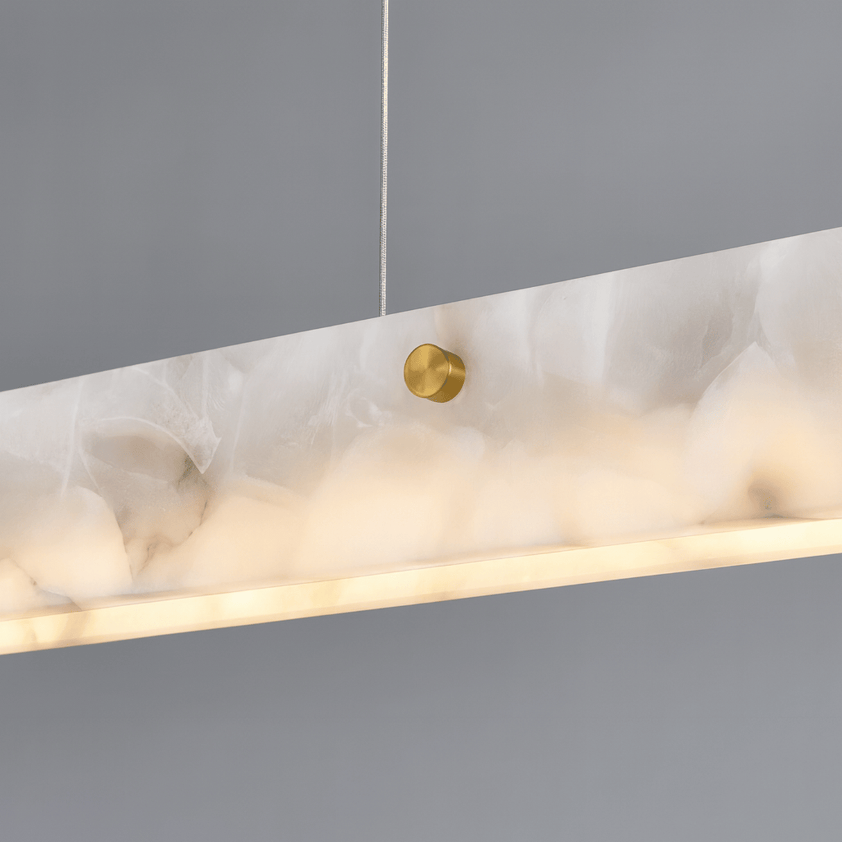 Marble-textured pendant light with gold fixture on a gray background