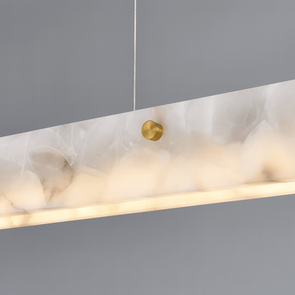 Marble-textured pendant light with gold fixture on a gray background