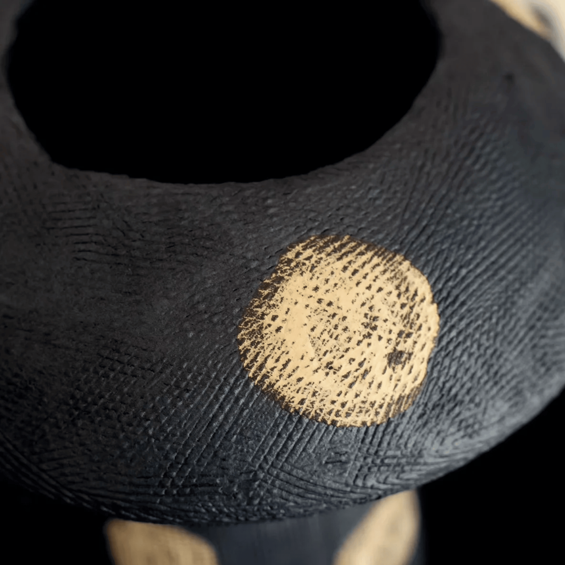 Black sock with a gold circular stain on a dark background