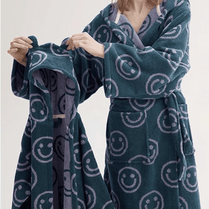 Person wearing a dark green robe with smiley face patterns on a plain background