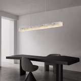 Modern black dining table with chairs in a minimalistic room with a pendant light.