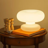 Table lamp on a wooden table with books and decorative items against a warm background