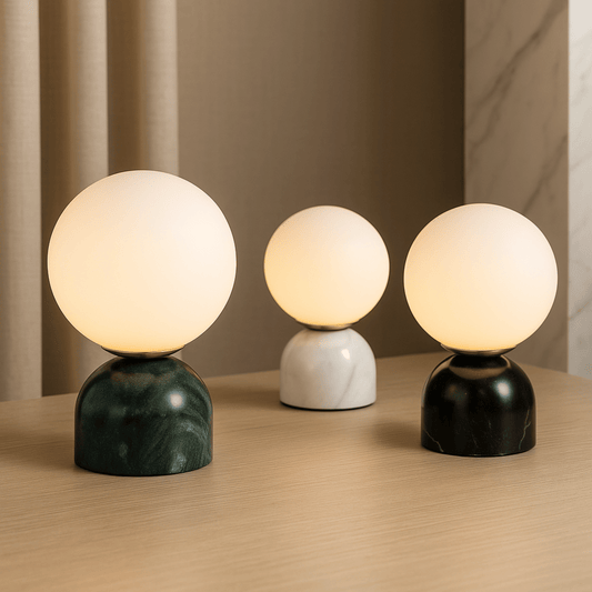 Three spherical table lamps with marble bases on a wooden surface.
