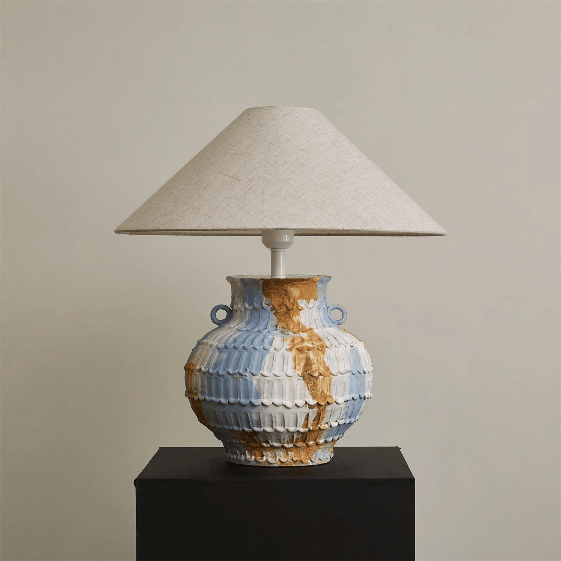 Table lamp with a ceramic base and beige lampshade on a plain background