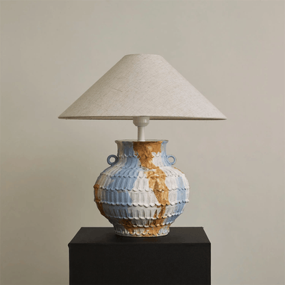 Table lamp with a ceramic base and beige lampshade on a plain background