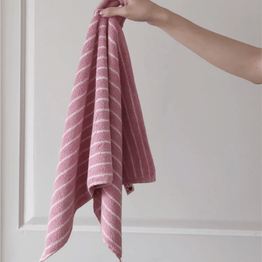 Pink striped towel held by a hand against a white background