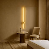 Modern interior with a wall-mounted light fixture, round table, and chair in a warm-toned room.