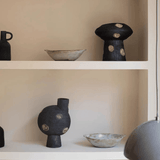Ceramic vases and bowls on a shelf against a beige wall