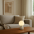 Table lamp on a wooden coffee table in a living room with a couch and abstract art in the background.