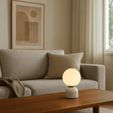 Table lamp on a wooden coffee table in a living room with a couch and abstract art in the background.