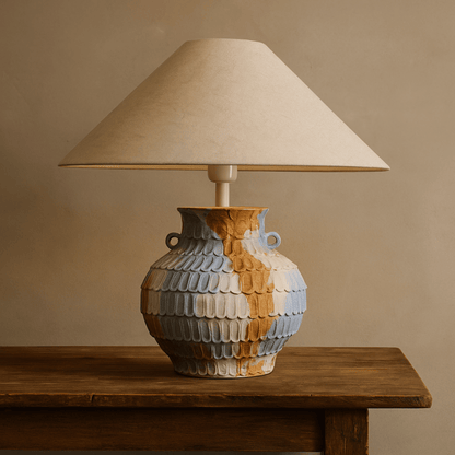 Decorative lamp with a ceramic base on a wooden table against a beige wall