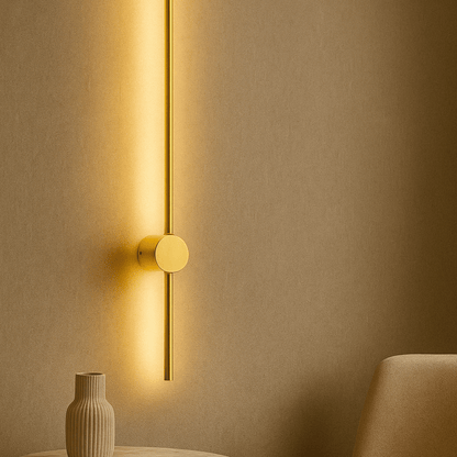 Gold wall-mounted light fixture casting a warm glow on a beige wall.