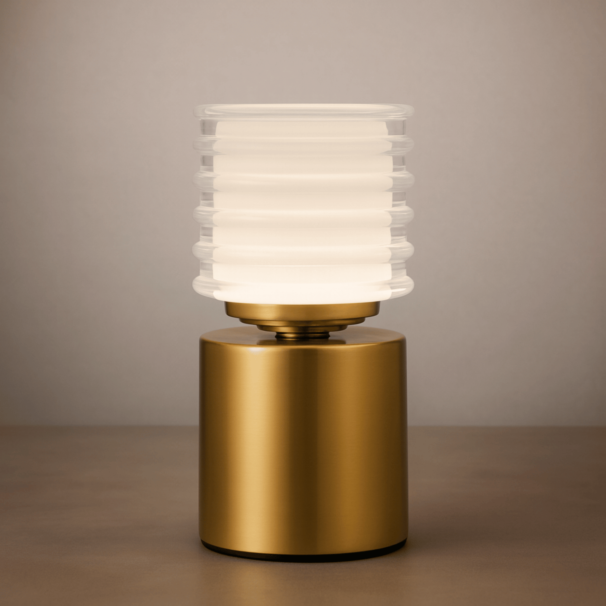 Table lamp with gold base and ribbed white glass shade on a neutral background