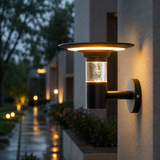 Outdoor wall light fixture on a building exterior with a blurred garden background